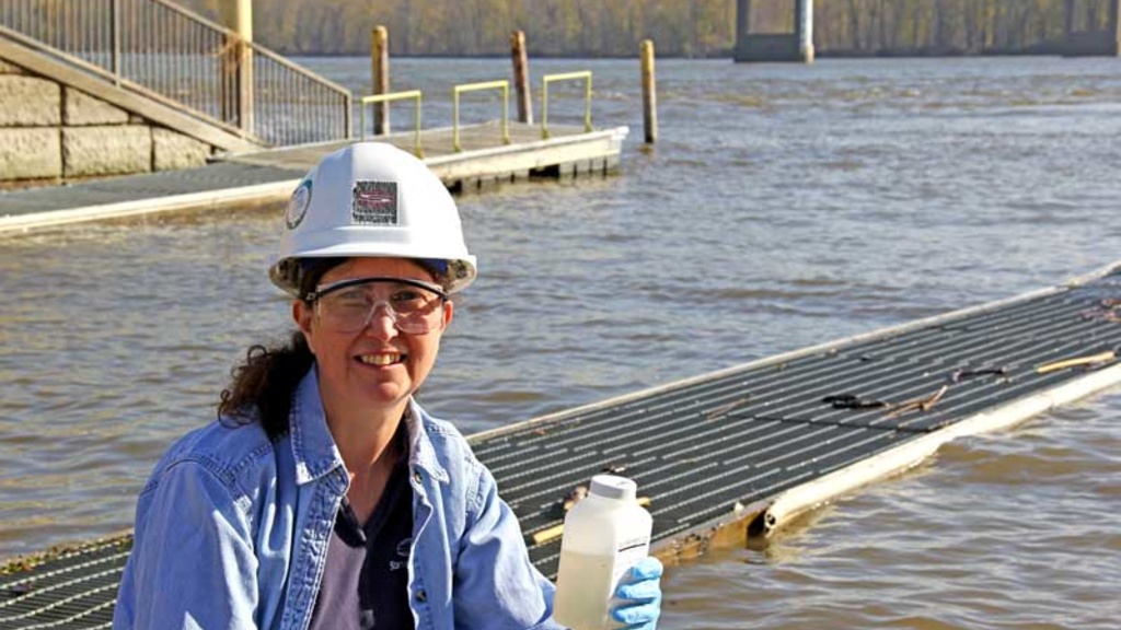 Becky Svatos wearing a hard hat in front of a body of water