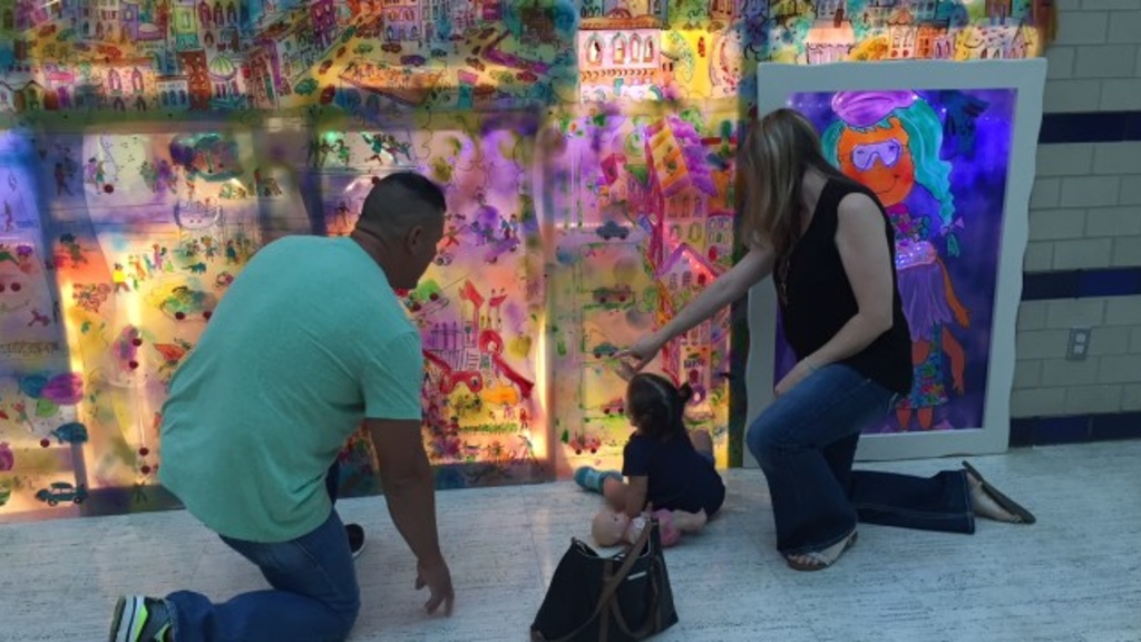 A family viewing the interactive STEAM mural.