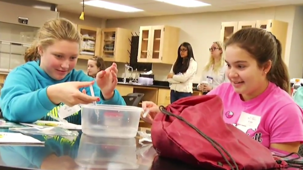 Two young girls holding water droppers in a science lab.