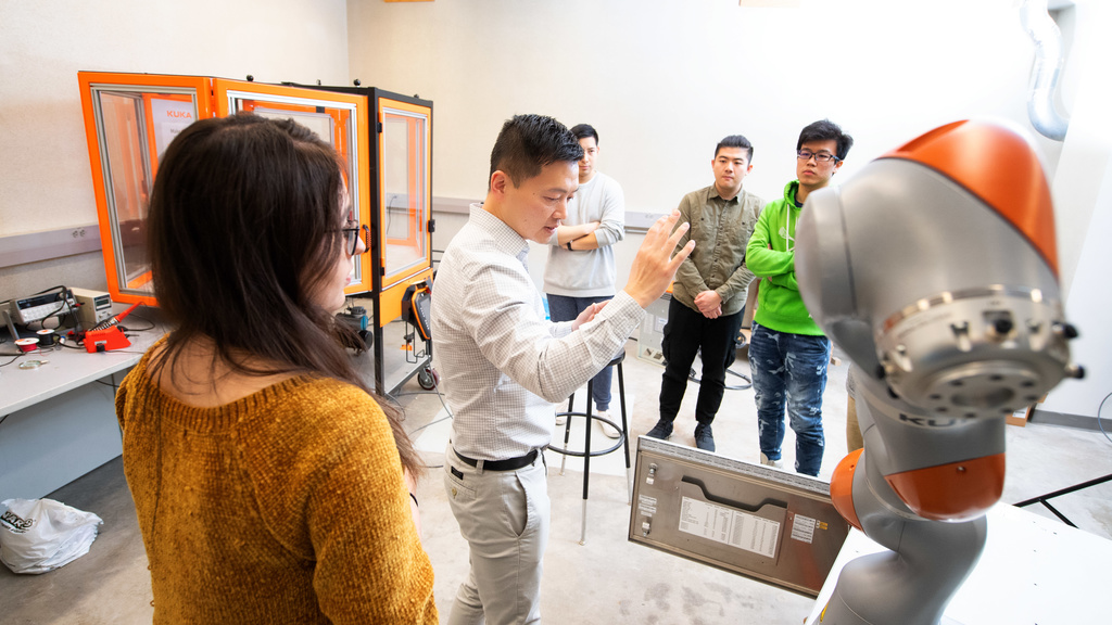 professor xiao works with students on kuka robot