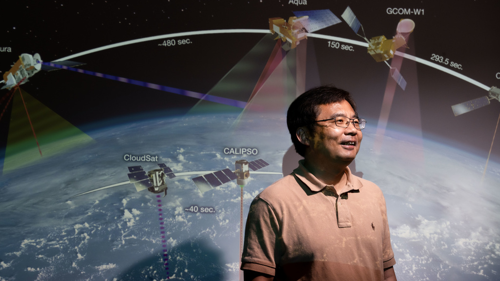 Professor stands in front of space and satellite image 