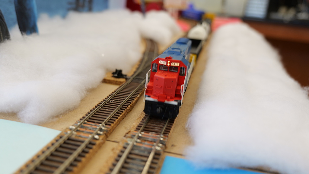 Model train on tracks approaches foreground