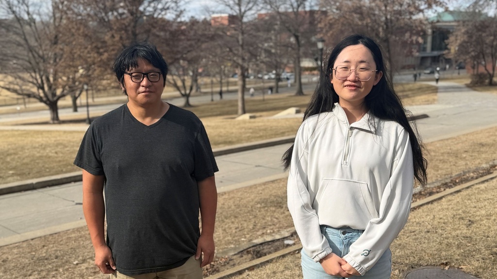 A man and woman pose with an outdoor background