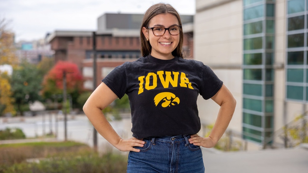 Student wearing an Iowa T-shirt standing outdoors on campus.