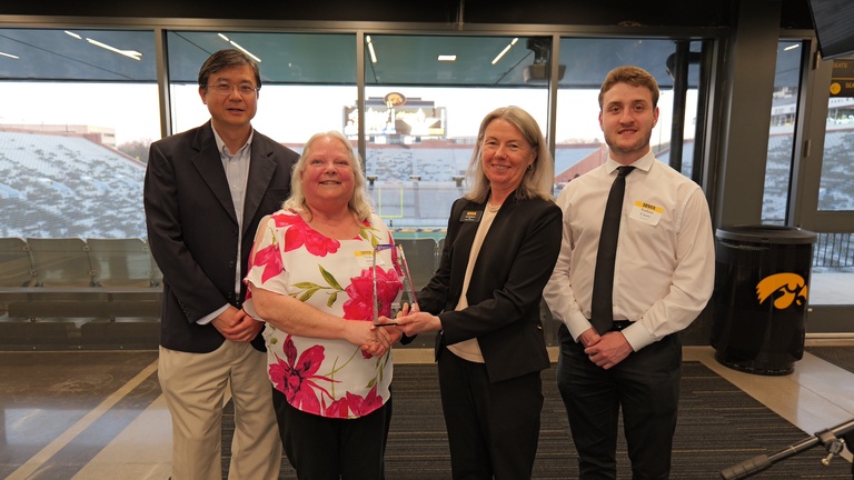 Award recipient poses with an award alongside three others during the recognition event.