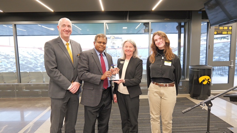 Award recipient poses with three others while displaying an award at the ceremony.