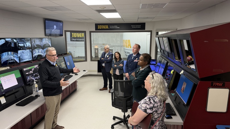 Group of visitors listens to a presentation inside the University of Iowa National Advanced Driving Simulator control room.